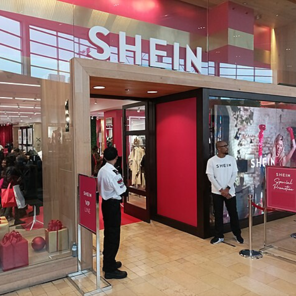 Workers at Shein factory operating sewing machines under bright lights